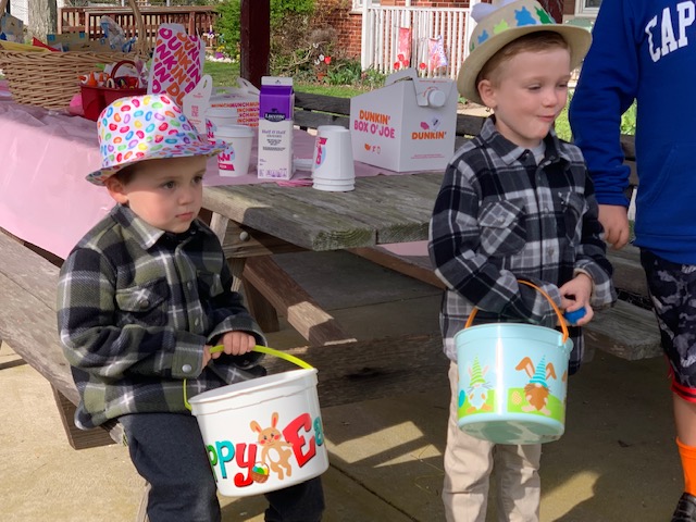 two boys holding buckets while going Easter egg hunting