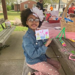 young girl holding up easter painting she made