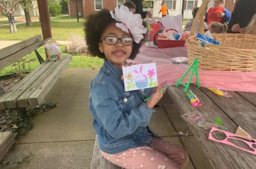 young girl holding up easter painting she made