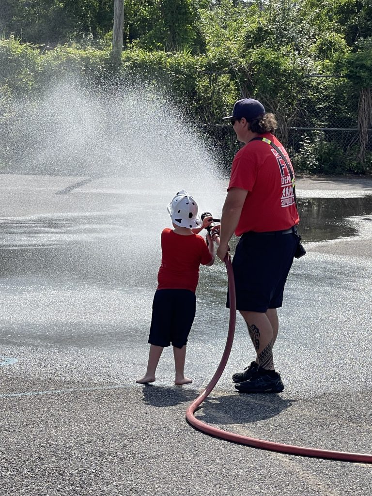 firefighter and little boy shooting fire hose