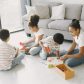 4 kids sitting on the ground playing with toys